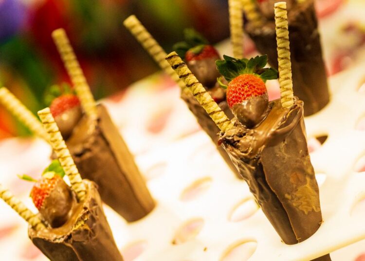 Praça de alimentação com bolos, tortas de morango, churros e chopp
