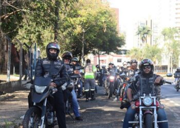 Motociclistas do grupo abordando condutores e distribuindo materiais educativos sobre trânsito