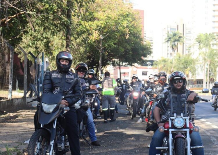 Motociclistas do grupo abordando condutores e distribuindo materiais educativos sobre trânsito