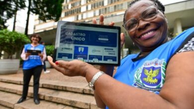 Entrevistadora segurando tablet em treinamento com colete azul e crachá