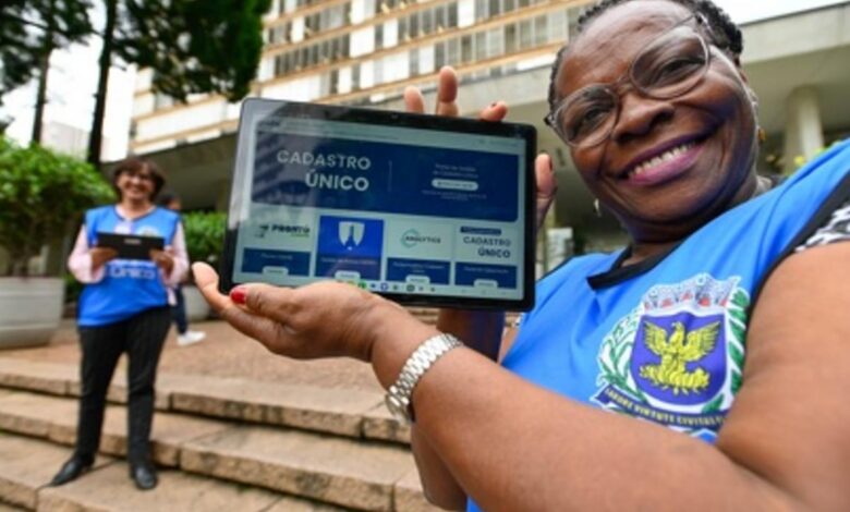 Entrevistadora segurando tablet em treinamento com colete azul e crachá