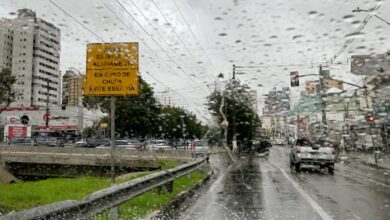 Vista da avenida Orosimbo Maia em dia chuvoso com veículos e proteção da Defesa Civil