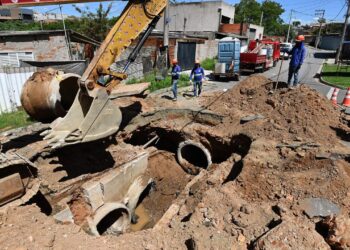 equipes de manutenção trabalham na galeria de águas pluviais e pavimento asfáltico durante reparos