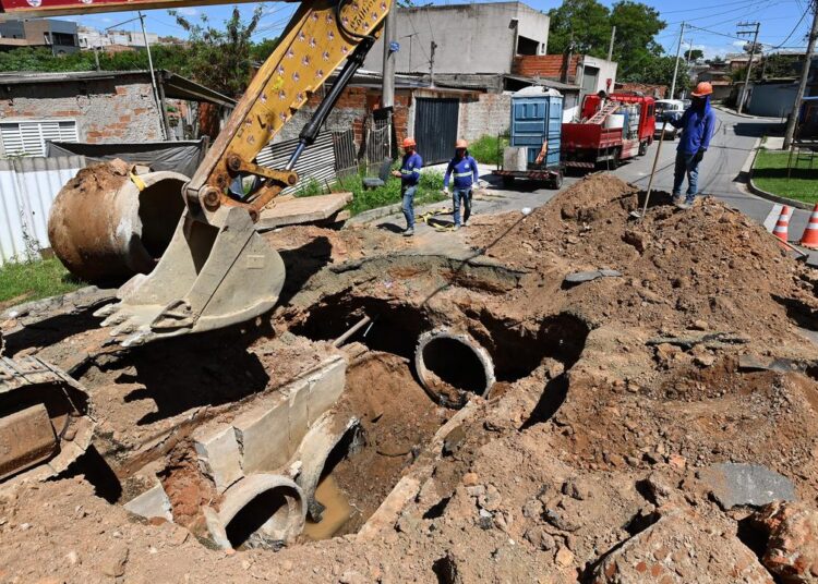 equipes de manutenção trabalham na galeria de águas pluviais e pavimento asfáltico durante reparos