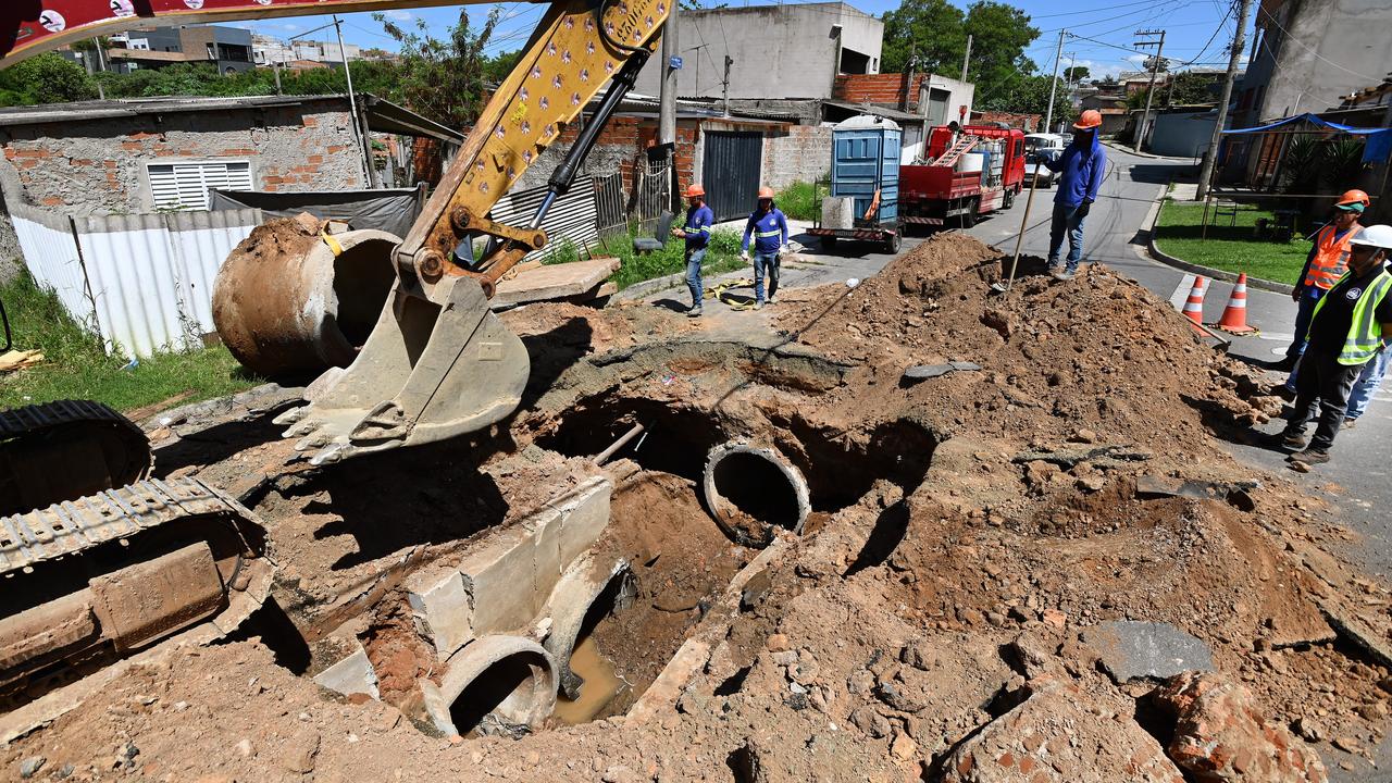 equipes de manutenção trabalham na galeria de águas pluviais e pavimento asfáltico durante reparos